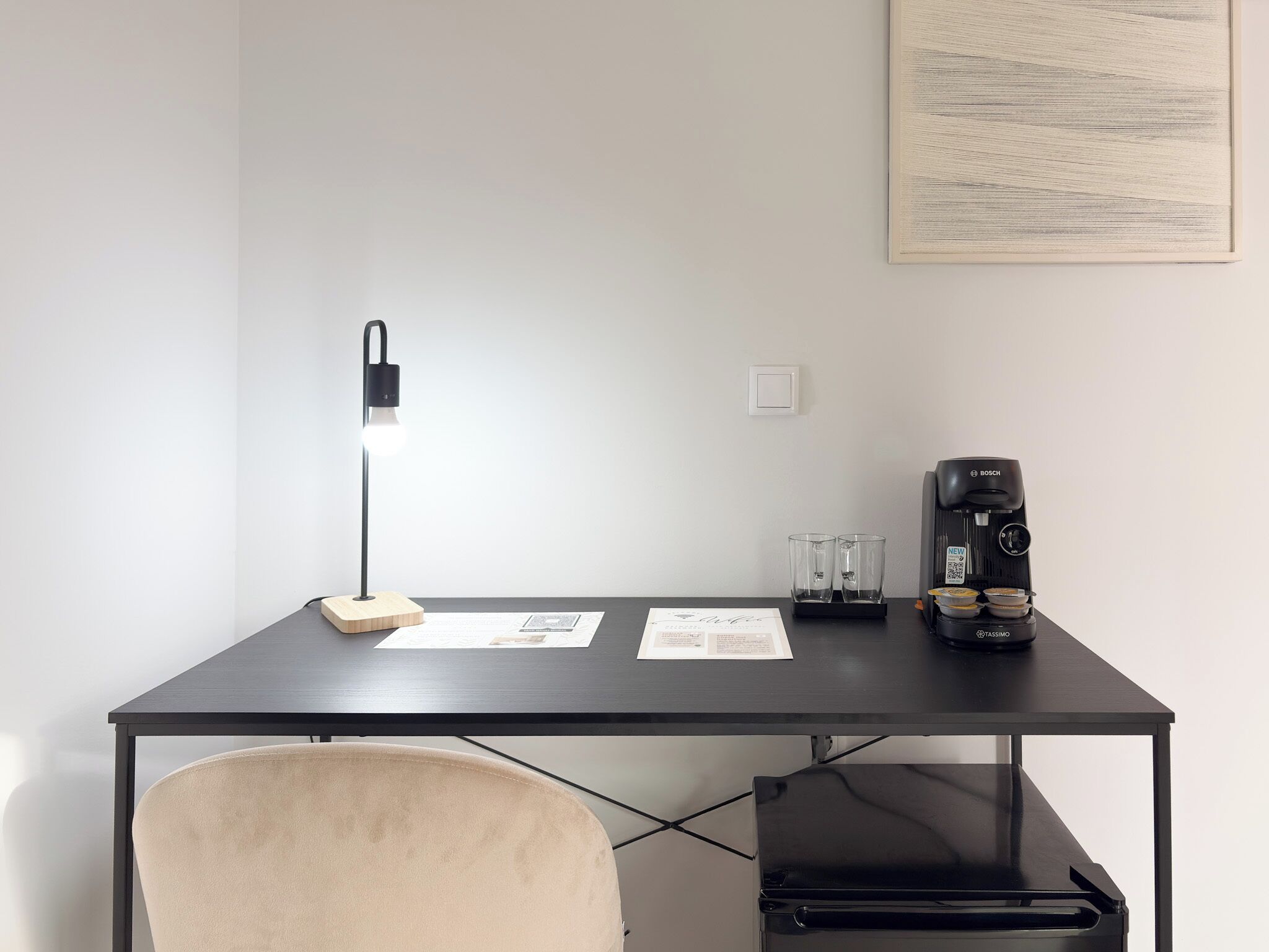Un espace de travail moderne comprenant un bureau, une chaise, une lampe, une machine à café et des documents.
