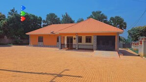 Une maison à deux étages, avec un toit recouvert de tuiles, un porche à l’avant et une allée pavée.