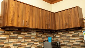 A kitchen with wooden cabinets and a stone backsplash. - Alfred Villas Gulu Five Bed Room Furnished House (Gulu City)
