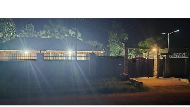 A gated property at night with a well-lit entrance and a metal fence. - Alfred Villas Gulu Five Bed Room Furnished House (Gulu City)