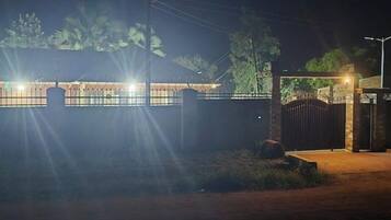 A gated property at night with a well-lit entrance and a metal fence.