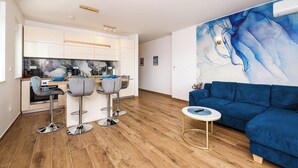 Une cuisine moderne avec des meubles blancs, un plan de travail en bois et un coin bar équipé de deux tabourets.