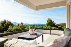 A balcony with a table, a bottle of champagne, and glasses, overlooking a scenic landscape with trees and mountains. - View of the "heart island" Croatia, Turanj, Welcome to Apartment ELA (Turanj)