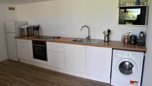 A compact kitchen with a dishwasher, sink, and a microwave on the countertop. - Villa Kokoro - Monstera room (Saint-Paul)