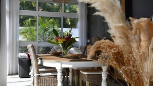 A dining area with a white table, wicker chairs, and a vase of flowers. - Villa Kokoro - Monstera room (Saint-Paul)