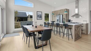 A modern kitchen with a large island, bar stools, and a dining table with chairs.