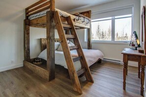 A bunk bed with a wooden ladder, a bedside table, and a window with a view of trees. - Remontée | Tavata Chalets | Valinouët (Saint-David-de-Falardeau)
