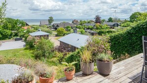 A coastal residential area with houses, a wooden deck, and a view of the sea. - 5 Star Holiday Home in Sjolund (Sjølund)
