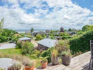 Ein Küstenwohngebiet mit Häusern, einer Holzterrasse und Blick auf das Meer.