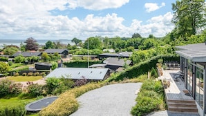 A residential area with houses, a paved driveway, and a view of the sea. - 5 Star Holiday Home in Sjolund (Sjølund)