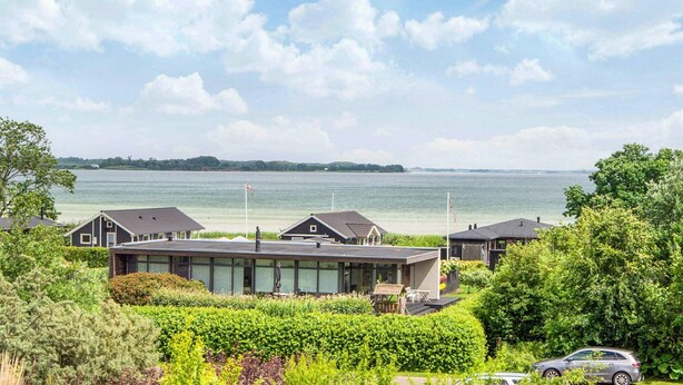 A coastal residential area with modern houses, a clear sky, and a view of the sea. - 5 Star Holiday Home in Sjolund (Sjølund)