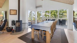 Una habitación amplia con una gran mesa de comedor, sillas de madera, una chimenea y ventanas grandes que ofrecen vistas al exterior.