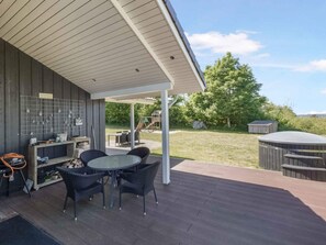 An outdoor patio with a table and chairs, a grill, and a covered area with a view of the backyard. - 5 Star Holiday Home in Skals (Skals)