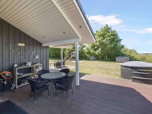 A covered patio area with a table and chairs, a grill, and a storage unit. - 5 Star Holiday Home in Skals (Skals)