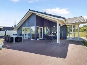 A modern house with a large deck, a covered patio, and a dining area with outdoor furniture. - 5 Star Holiday Home in Skals (Skals)