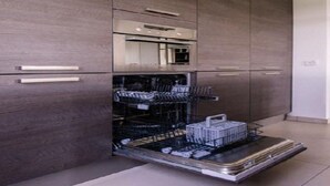 Una cucina moderna con mobili in legno scuro, forno integrato e lavastoviglie.