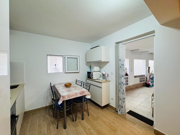 A compact kitchen with a dining table, chairs, and a microwave.