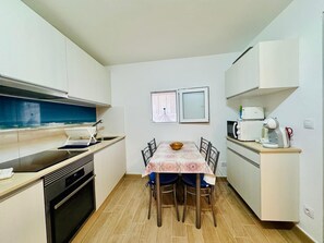 A compact kitchen with a dining table, chairs, a microwave, and a coffee maker.