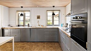 Una cucina moderna con mobili grigi, soffitto in legno e una grande finestra.