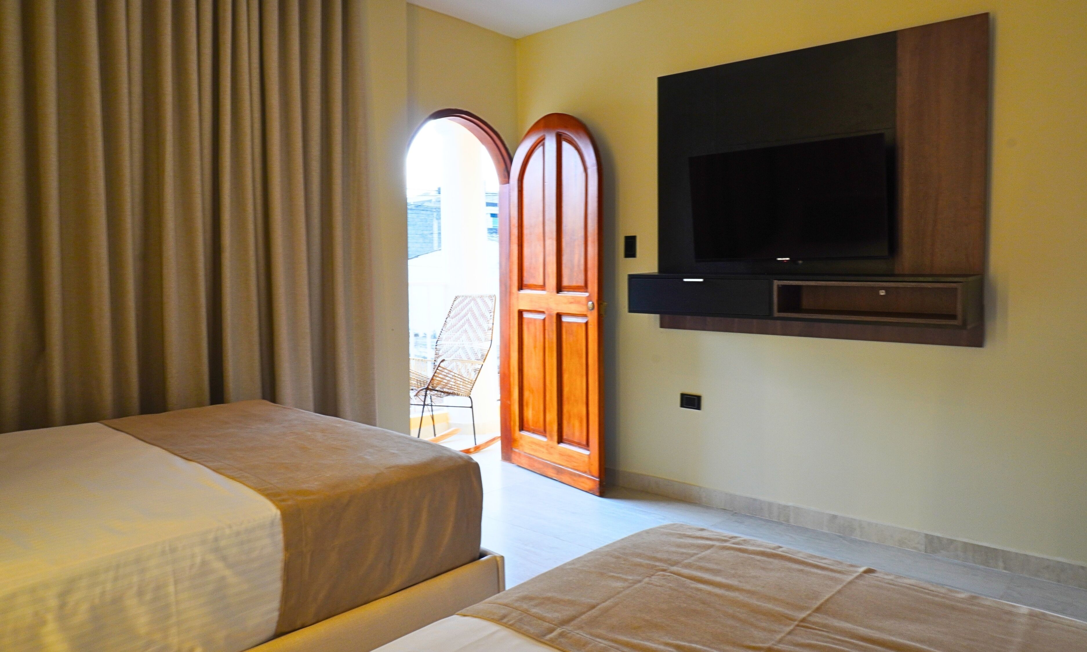 Une chambre d’hôtel avec deux lits, un téléviseur fixé au mur et une porte donnant sur un espace extérieur.