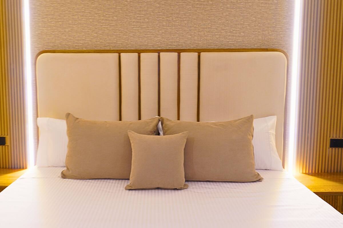 Un lit avec une tête de lit, deux oreillers et une table de chevet.