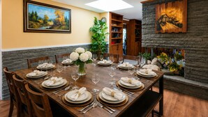 A dining room with a long wooden table set for a meal, surrounded by chairs.