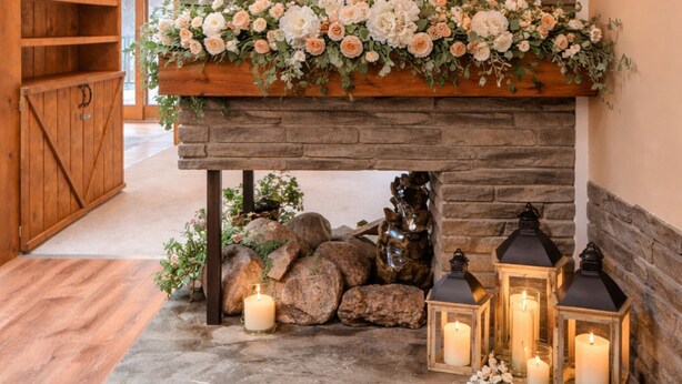 A stone fireplace with a mirror, candles, and lanterns.