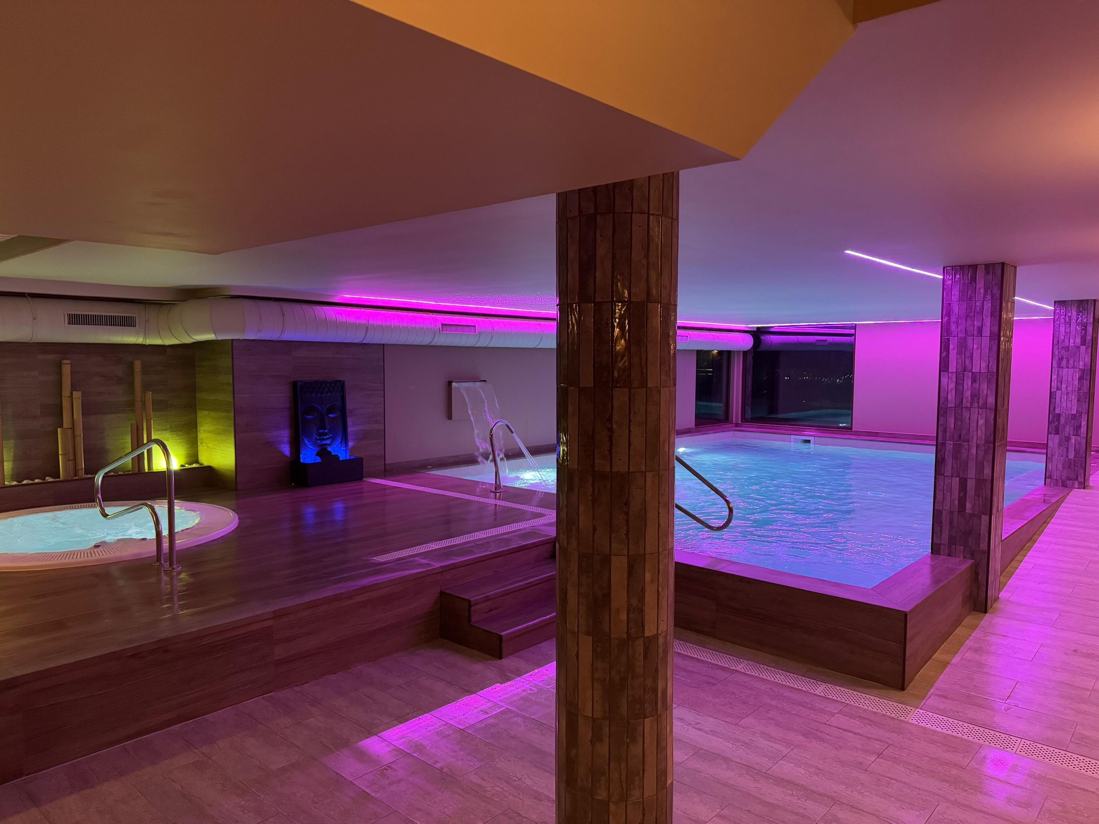 Ein Wellnessbereich mit Whirlpool, Holzboden und Blick auf den Nachthimmel.
