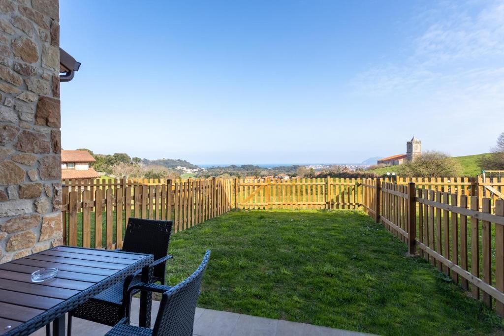 Un patio con una mesa, sillas, un muro de piedra y una cerca de madera.