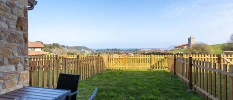 A patio with a table and chairs, a stone wall, and a wooden fence.