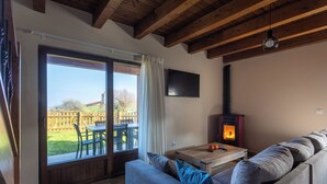 A living room with a sofa, a table with a fire, a TV on the wall, and a sliding glass door to the outside. - Villas Spa el Mirador de Isla (Isla)