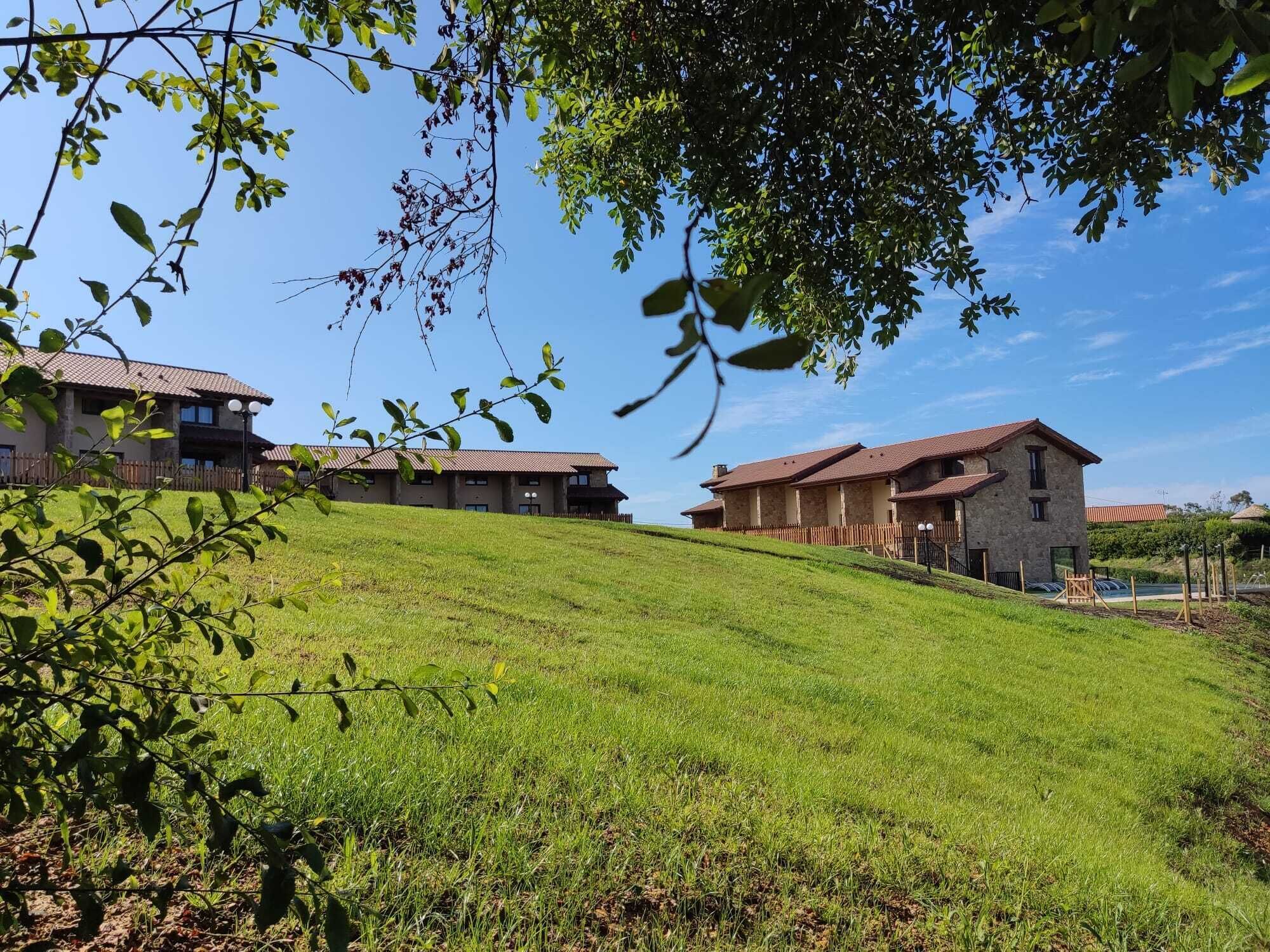 A hillside with a row of stone buildings, each with a red-tiled roof.