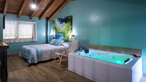A bedroom with a bed, a chair, a bathtub, and a painting on the wall. - Villas Spa el Mirador de Isla (Isla)