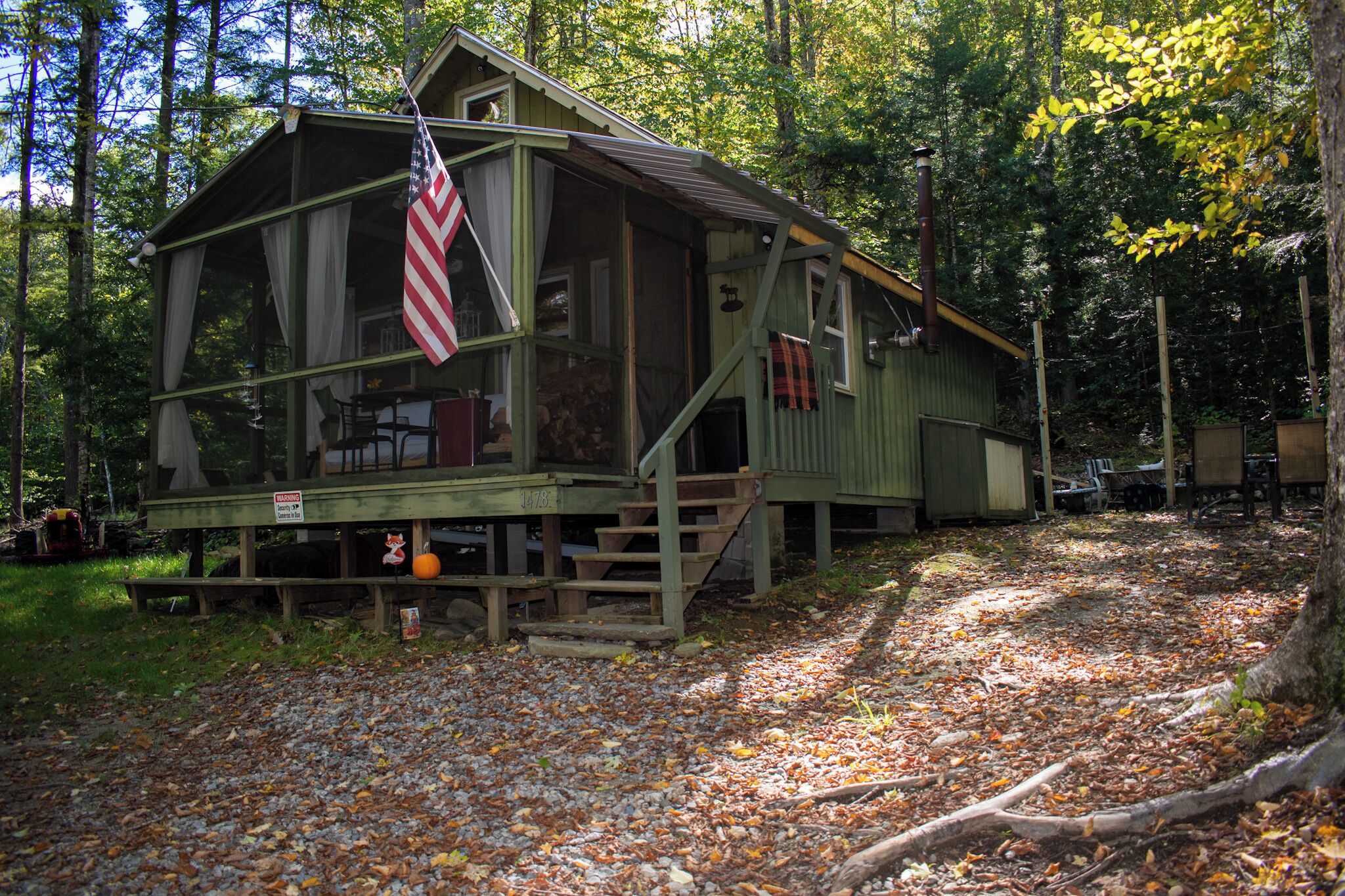 A rustic cabin with a porch, wooden steps, and a flag.