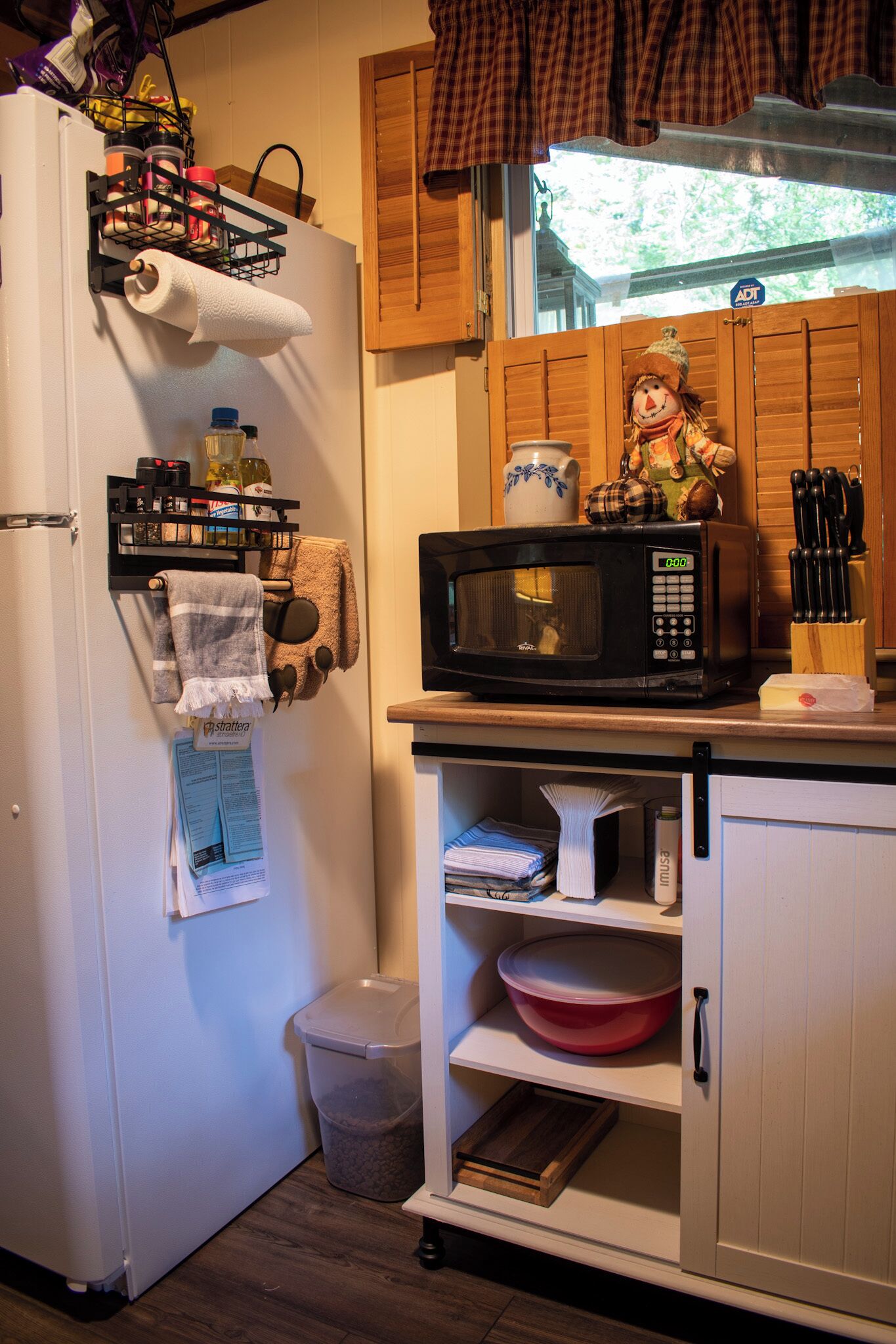 Una cocina con microondas, un cubo de basura y un armario de madera.