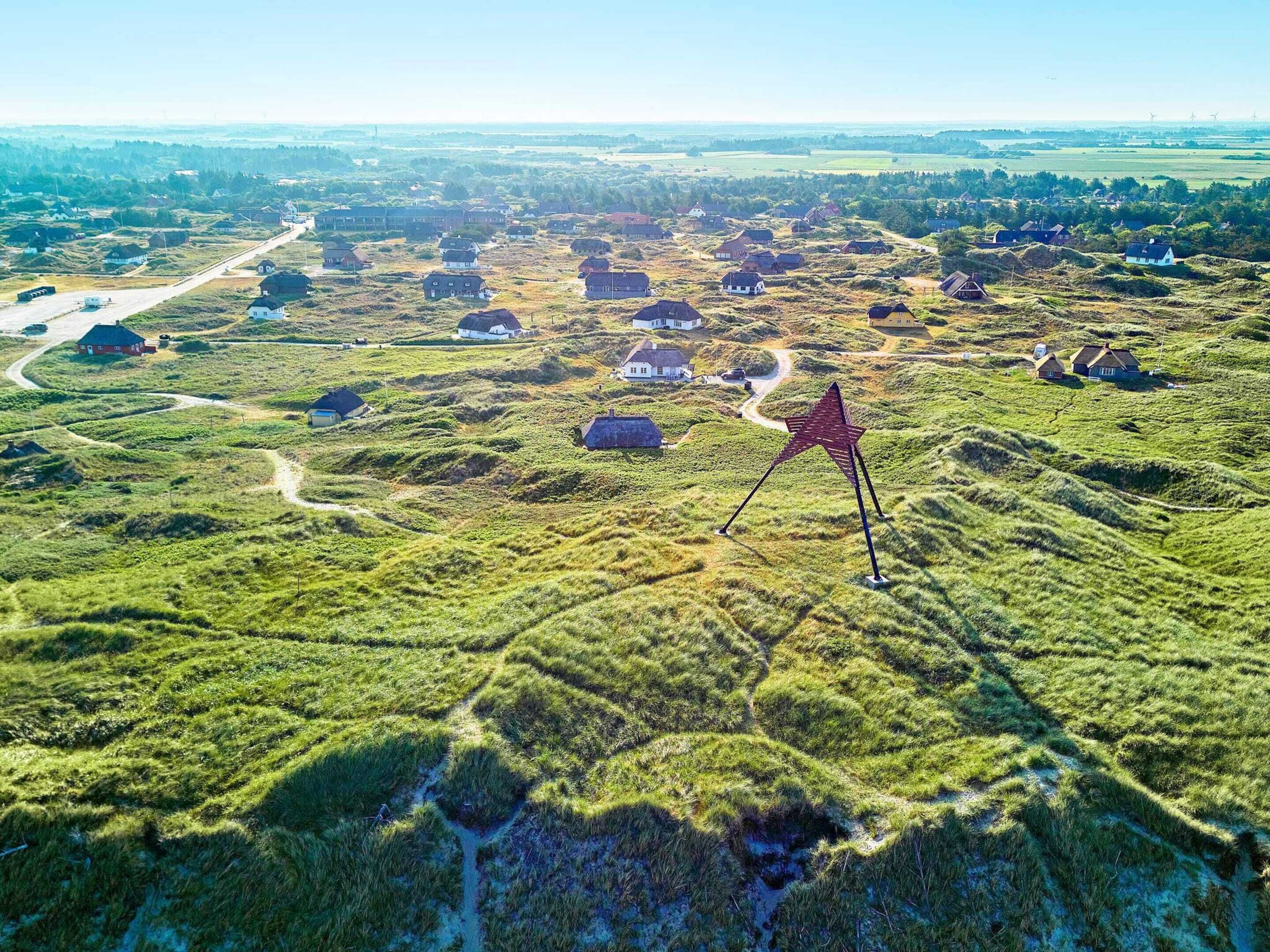 An aerial view of a rural area with scattered houses and a prominent red star-shaped structure.