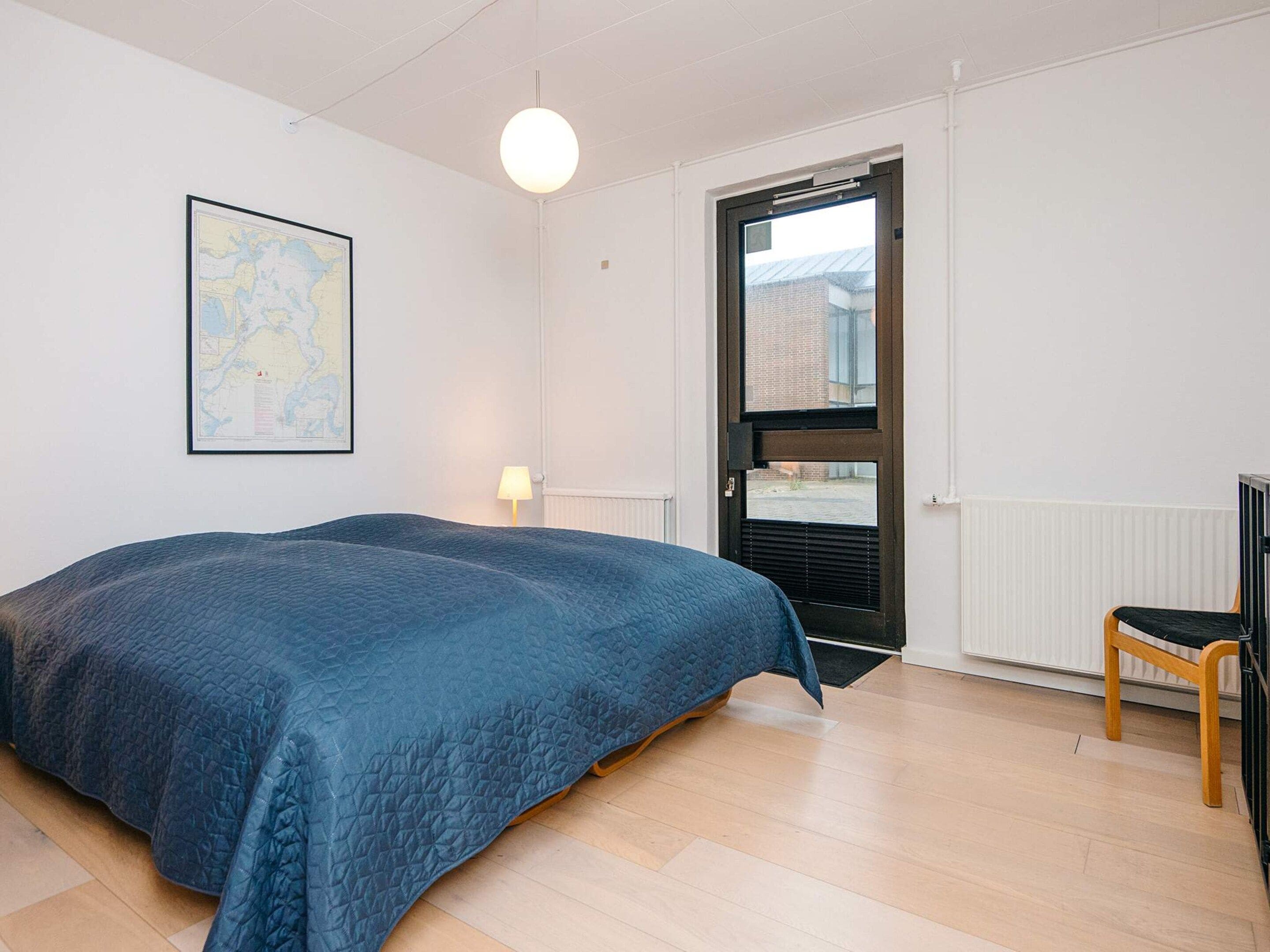 Un dormitorio con una cama, un mapa en la pared, una puerta y una silla.