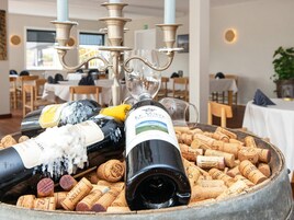 Mesa com garrafas de vinho e rolhas em área de jantar com lustre.