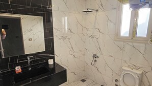 A modern bathroom with a black marble vanity, a large mirror, a shower with a glass door, and a toilet with a bidet attachment. - happy villa for families only (Alexandria)