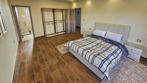 A bedroom with a large bed, a wardrobe, a bathroom, and a door leading to another room. - happy villa for families only (Alexandria)