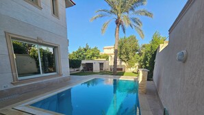 A swimming pool with a clear blue water surface, surrounded by a stone deck. - happy villa for families only (Alexandria)
