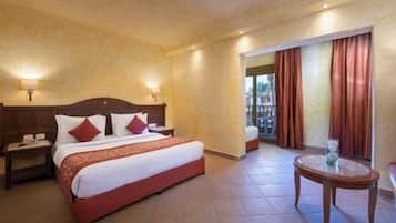 Habitación de hotel con cama, mesitas de noche, una mesa redonda y vistas al exterior.