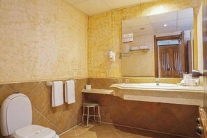 Un baño con inodoro, lavamanos y espejo.