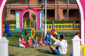 Children playing in a colorful outdoor play area with a building in the background. - Charmillion Sea Life Resort (Qesm Sharm Ash Sheikh)