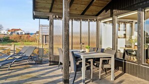 Eine Terrasse im Freien mit Tisch und Stühlen, ein Holzdeck und Blick auf die Umgebung.