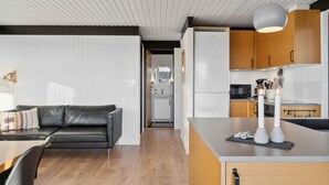 Eine moderne Küche mit Holzausstattung, einem eingebauten Ofen und einem Essbereich mit einer schwarzen Ledersofa und einem Holztisch.