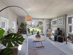 A modern living room with a sofa, a round coffee table, a fireplace, and a large window.