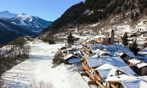 A snow-covered village with traditional wooden houses, a church, and a mountain in the background. - 3 Rooms for 6 People (Champagny-en-Vanoise)