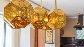 Een modern interieur met geometrische hanglampen, een houten deur en een kunstwerk in een lijst aan de muur.