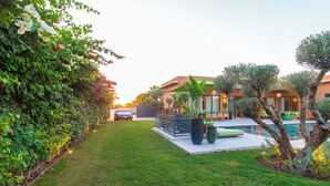 A well-maintained garden with a swimming pool, a car parked nearby, and a building with a modern design. - Villa Jamila Marrakech - Authentic luxury and heated private pool. (Marrakech)